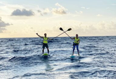 two paddle boarders with oars crossed