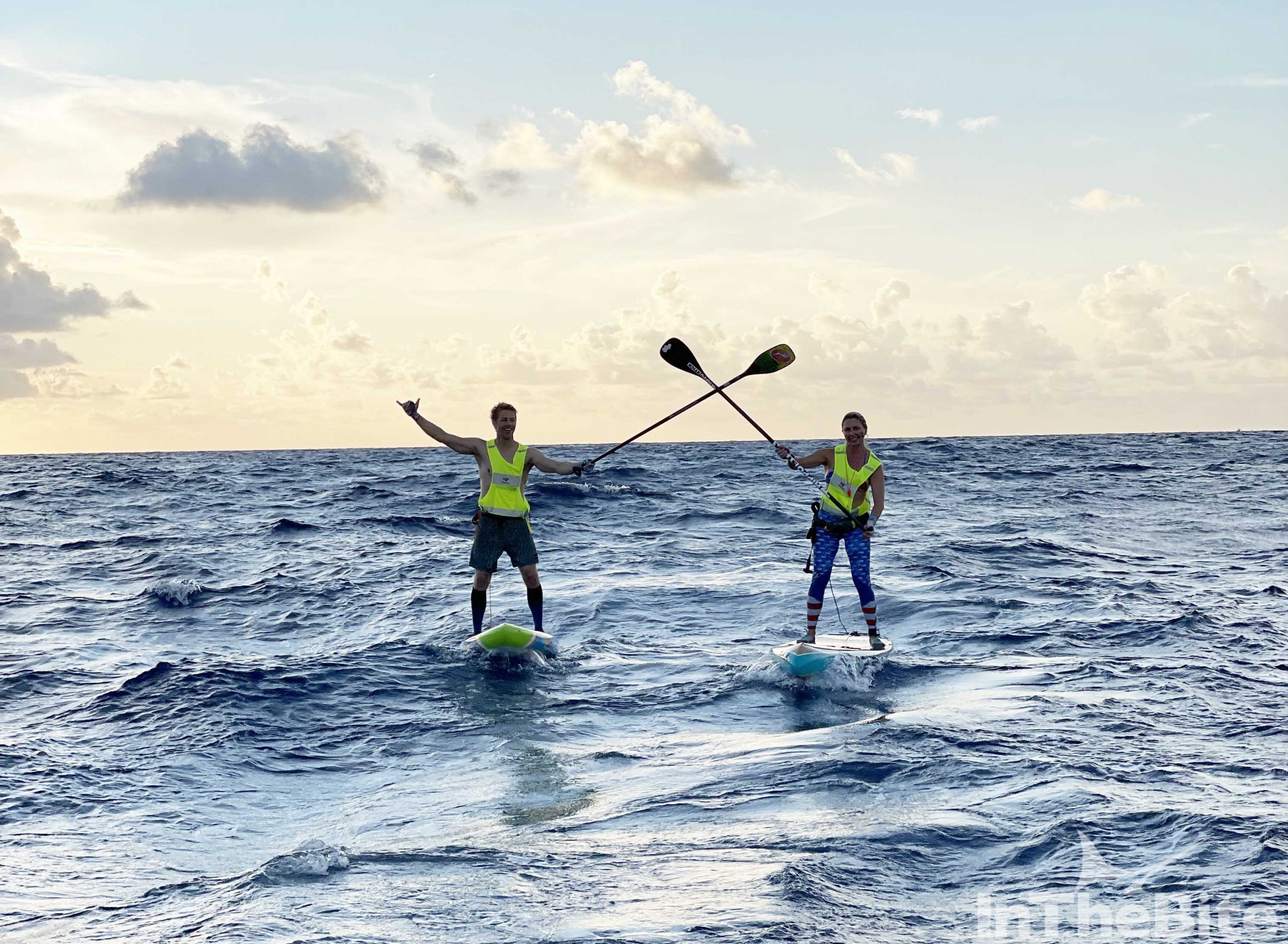 two paddle boarders with oars crossed