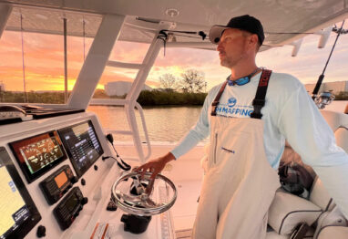 SiriusXM - Man stands at the wheel of a boat looking ahead while navigating waters