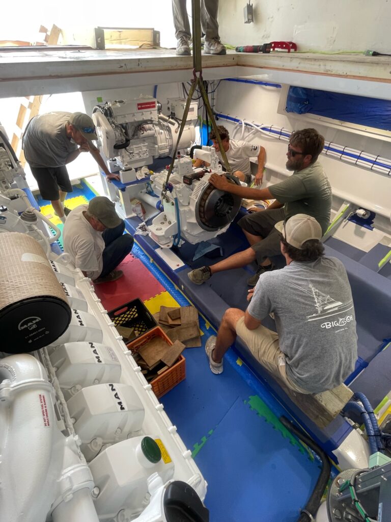 3 guys looking at a boat motor during the boat refit