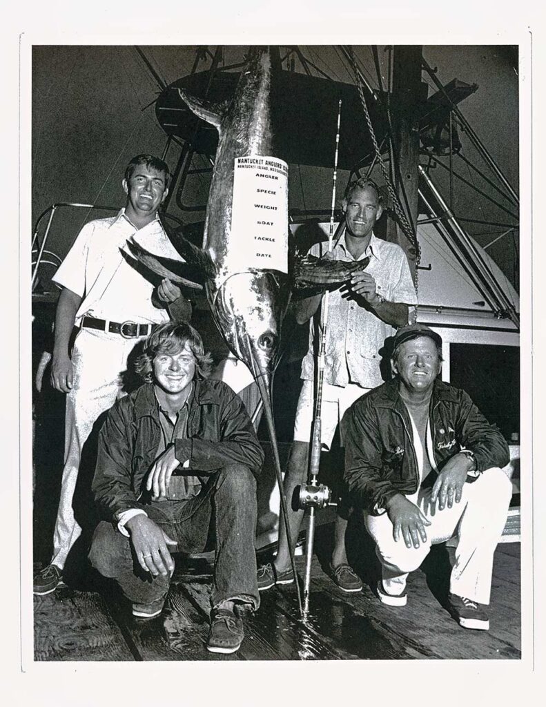 a Record Swordfish with The crew cf 4 guys around the hanging fish