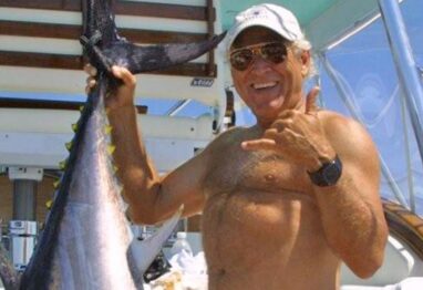 Jimmy Buffett smiling with fish next to him