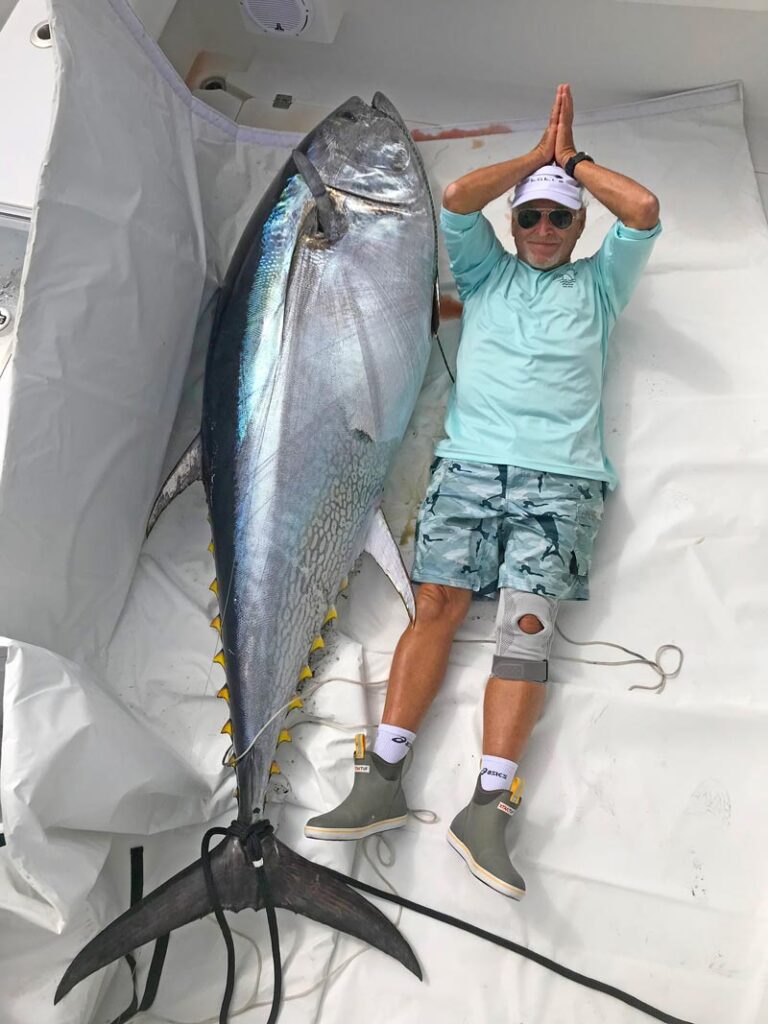 Jimmy Buffett lying next to bluefin tuna longer than him