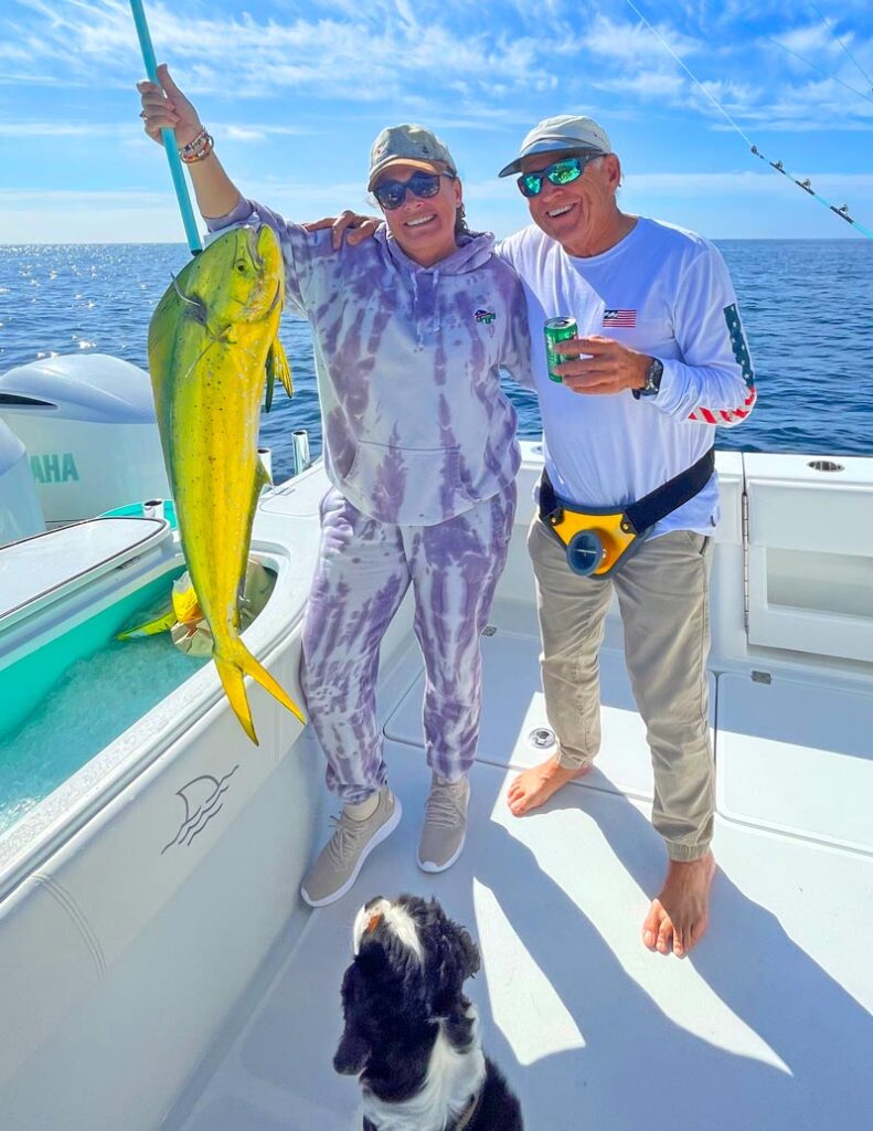 Jimmy Buffett and his daughter Savannah holding a nice colorful yellow mahi up with a gaff
