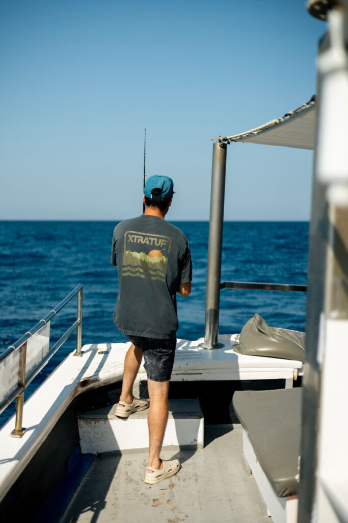a guy fishing off the back of the boat