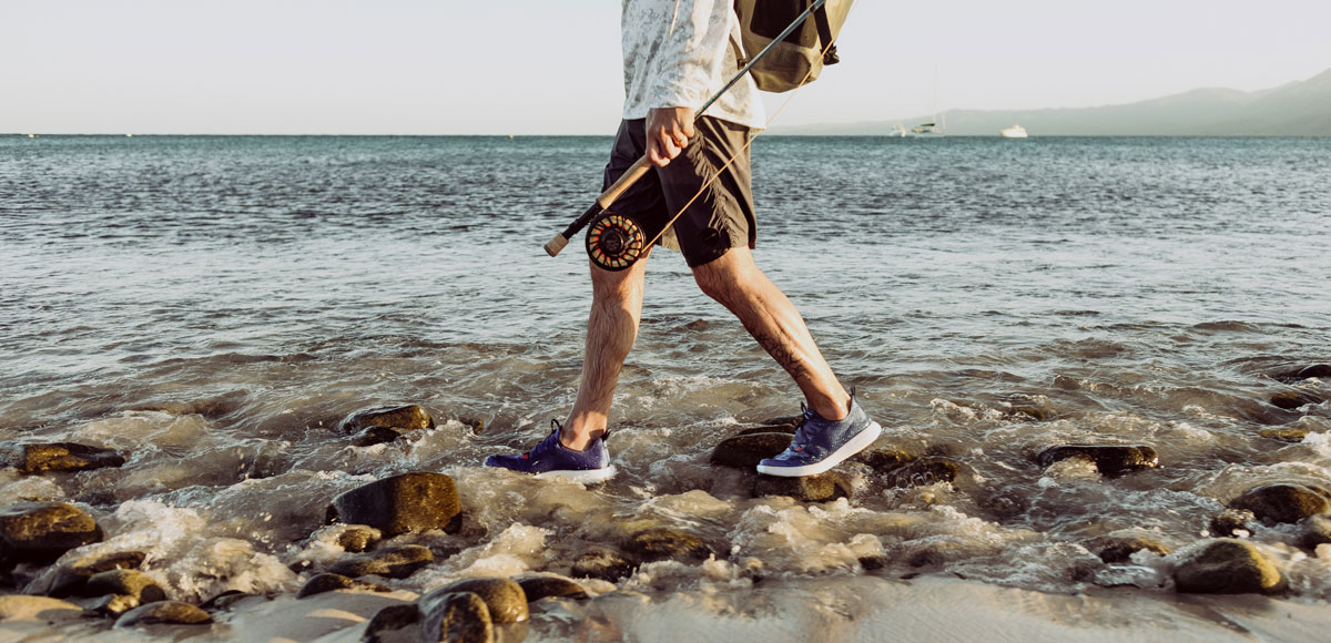 a guy walking with CrossCurrent Boat Shoes on rocks