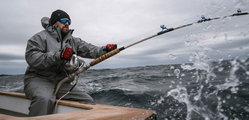 a man fighting a fish with a large fishing rod in foul weather