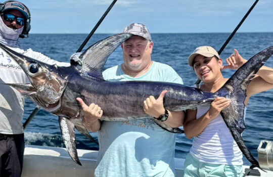 3 people holding up a nice swordfish on the ocean