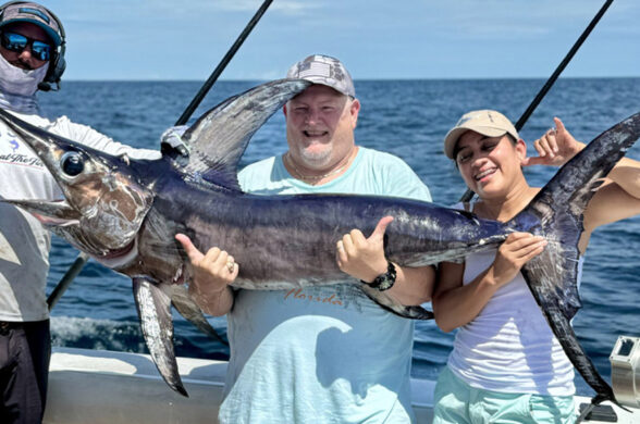 3 people holding up a nice swordfish on the ocean