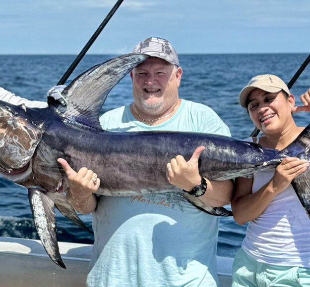 3 people holding up a nice swordfish on the ocean