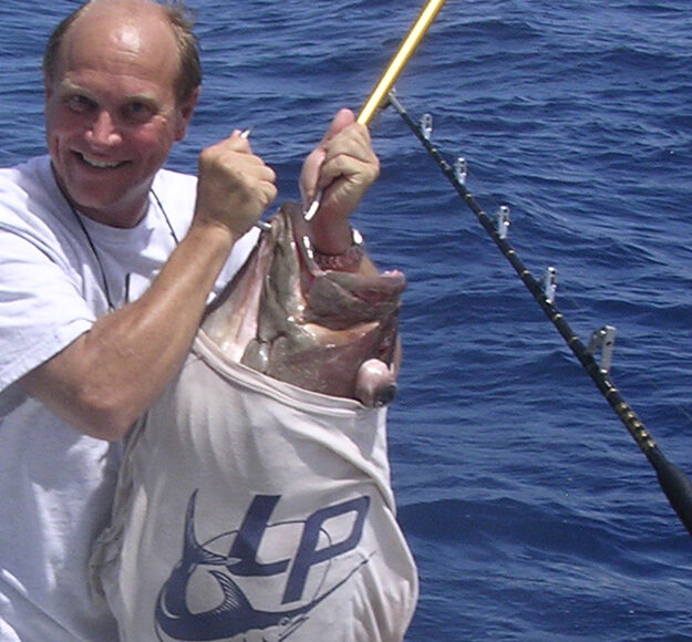 Lindgren Pitman's Peter Lindgren holding a big grouper with a LP t-shirt on the fish