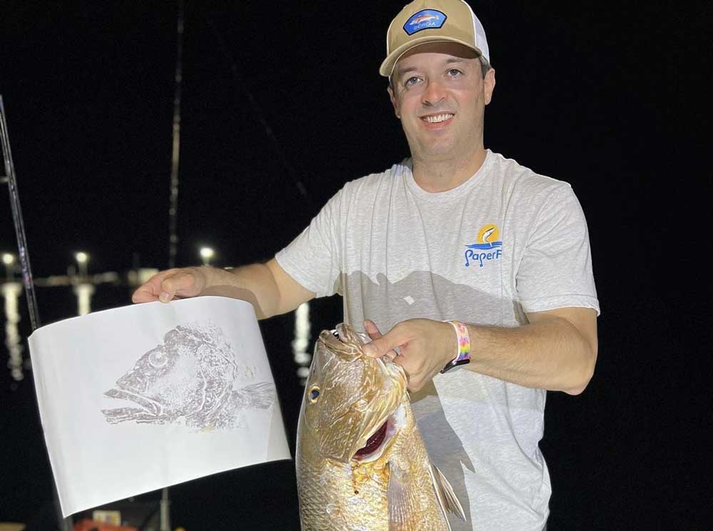 a guy holding Gyotaku Fish Printing and a golden fish
