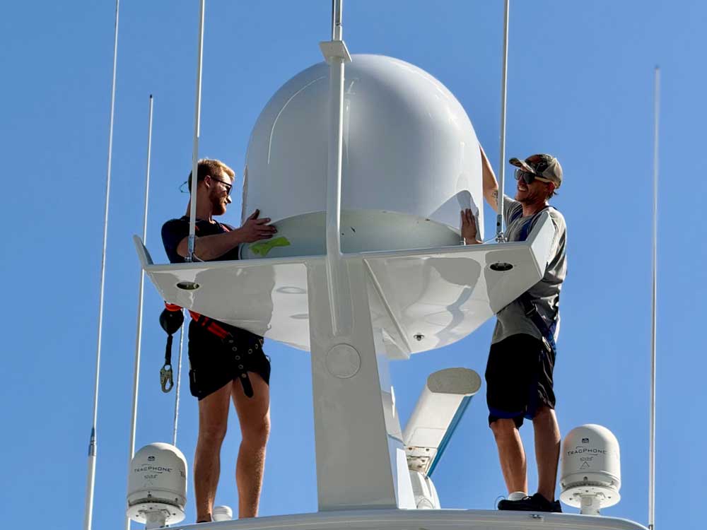 two guys placing a dome high atop a sportfishing boat