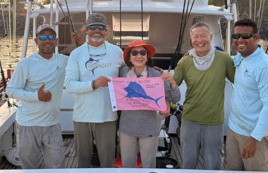 Helen Tang Sets New Sailfish Fly Record with 19 Releases holding thepink flag with the crew in this image