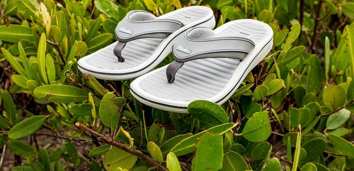 Huk Launches Rogue Island Flip Flop sitting on a green bush