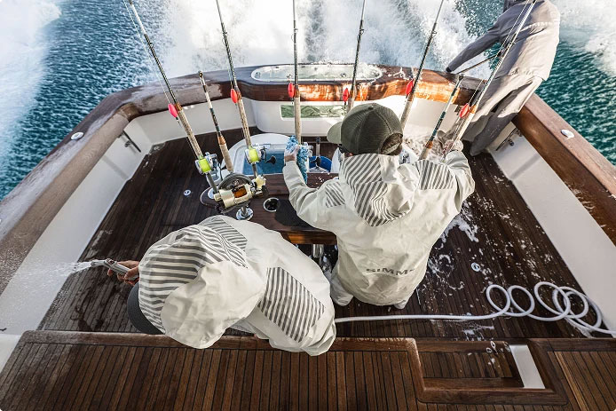 Simms Rip Line Pro foul weather gear being worn by two guys in the back of the boat