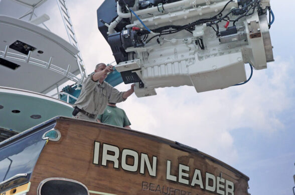 Technician guides a marine diesel engine being lifted out of the sportfishing yacht Iron Leader at Safe Harbor Jarrett Bay.