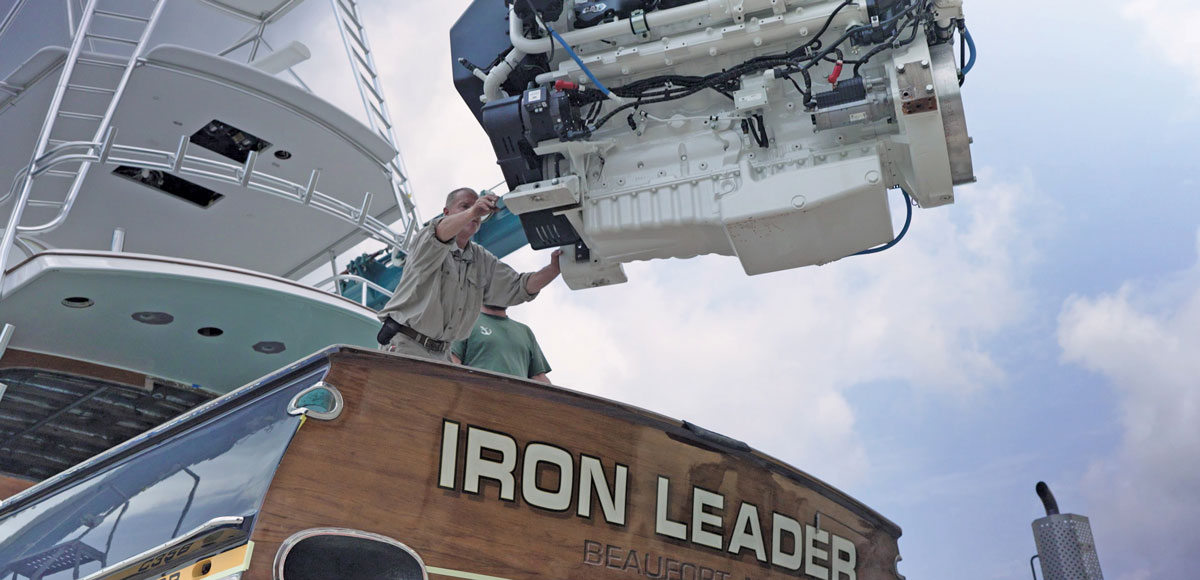 Technician guides a marine diesel engine being lifted out of the sportfishing yacht Iron Leader at Safe Harbor Jarrett Bay.