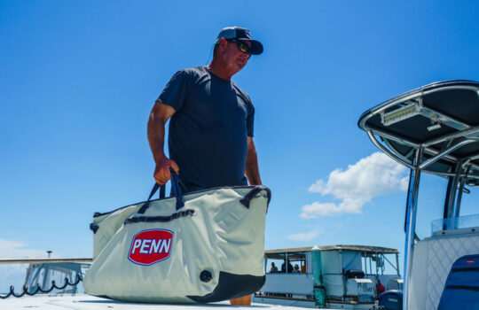 a fisherman carrying the PENN Ballast insulated catch cooler with side drain plug and Hypalon drag pads