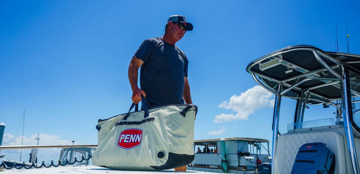 a fisherman carrying the PENN Ballast insulated catch cooler with side drain plug and Hypalon drag pads