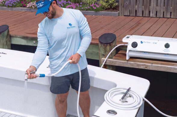 Crew member rinsing a sportfishing boat’s gunwale with freshwater from a Blue Water Desalination marine watermaker on the dock