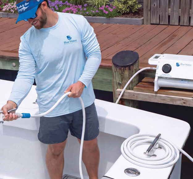 Crew member rinsing a sportfishing boat’s gunwale with freshwater from a Blue Water Desalination marine watermaker on the dock