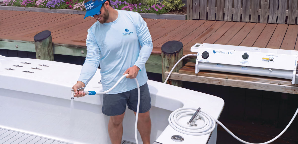 Crew member rinsing a sportfishing boat’s gunwale with freshwater from a Blue Water Desalination marine watermaker on the dock